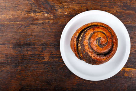 Bun with poppies in a plate on a wooden background. Top viewの写真素材
