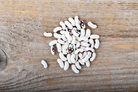 A pile of raw beans on a wooden background. Top view