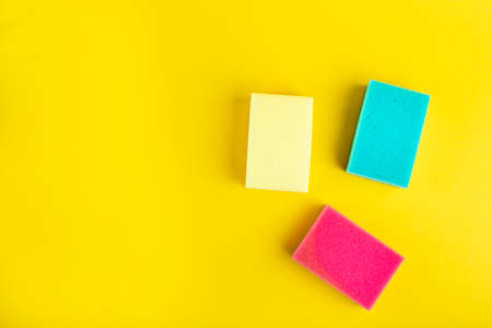 Multi-colored sponges for washing dishes and cleaning on a bright yellow background. space for textの写真素材