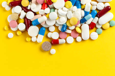 A lot of multi-colored tablets scattered on a yellow background. place for text. view from above
