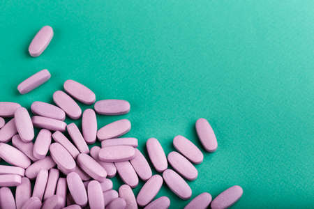 pink pills scattered on the green table. space for textの写真素材
