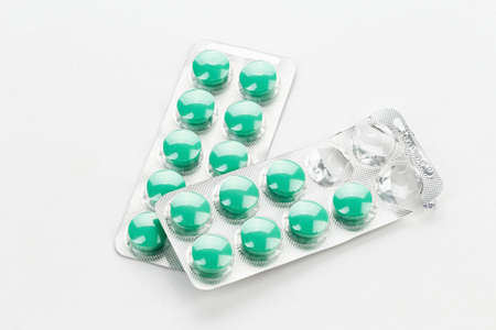 green pills in a blister on a white background. modern methods of treatment of diseases