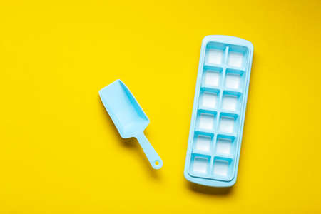 plastic form for freezing ice with a spatula on a yellow background. space for textの写真素材