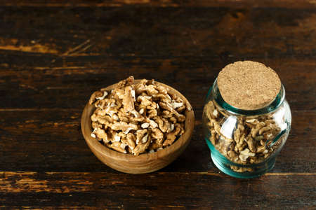 chopped walnuts on a table in a jar, on a brown wooden background. space for text