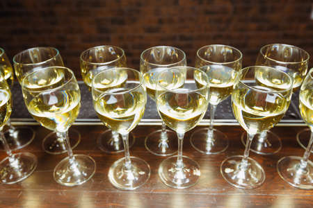 glasses of white wine are lined up on the bar. welcome drink