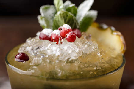 refreshing mojito cocktail with ice and mint in a glass on a wooden rack. cocktail decorated with cranberriesの写真素材