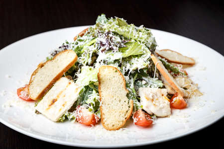 Traditional Caesar salad with chicken, bacon, lettuce letuk, croutons, onions, tomatoes, sprinkled with parmesan cheese.の写真素材