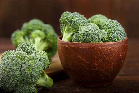 raw broccoli cabbage on a wooden background in a clay plate. rustic vegetable backgroundの写真素材
