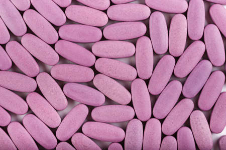 pink oval pills scattered as a background. clearly visible texture of the tablets. place for textの写真素材