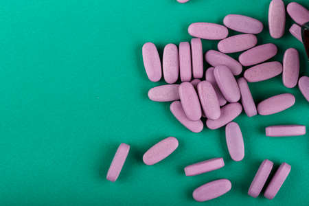 organic homeopathic pills scattered on a green background. place for textの写真素材