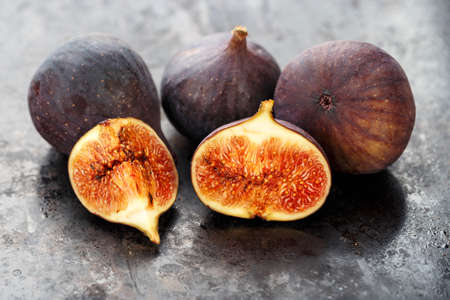 whole and sliced ripe fresh figs on a black table. close-up. the fruit texture is clearly visibleの写真素材