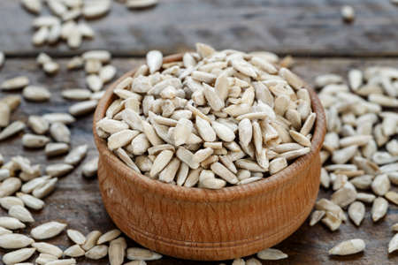 peeled sunflower seeds in a wooden plate on a wooden background. place for textの写真素材