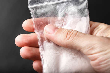 white powder drug in a small plastic bag in hand. place for text