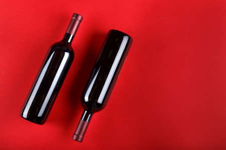 bottles with red wine without a label. on a red fouon. place for text