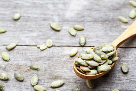 pumpkin seeds in a wooden spoon on a wooden background. view from above. place for textの写真素材