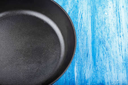 Fresh black cast-iron skillet on a wooden background. place for text