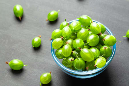 ripe gooseberries in a plate on a black background. place for textの写真素材