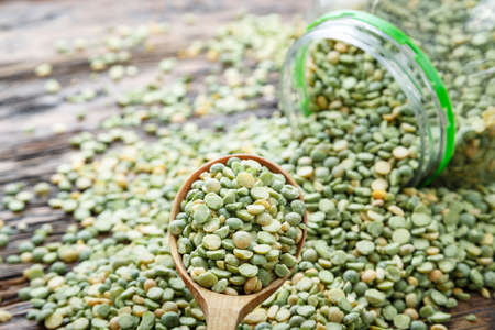 dry peas poured out of a can on a brown wooden background. place for text