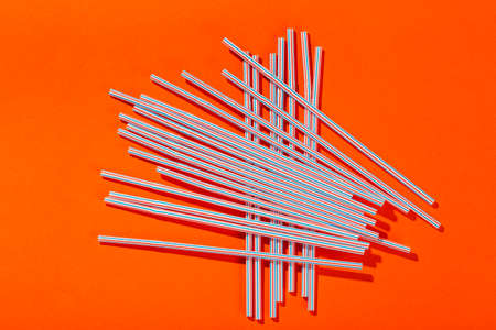 many plastic drinking straws are scattered on a bright background. place for text