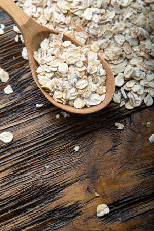 uncooked oatmeal in spoons brown wooden background. place for text