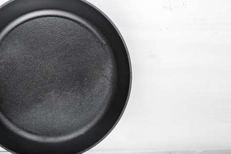 Fresh black cast-iron skillet on a wooden background. place for textの写真素材