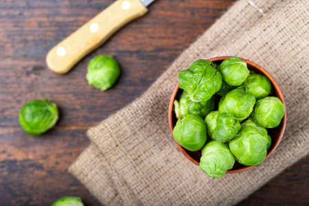 raw brussels sprouts in a plate on a burlap napkin, on wooden background. place for textの写真素材