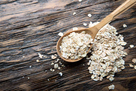 uncooked oatmeal in spoons brown wooden background. place for textの写真素材
