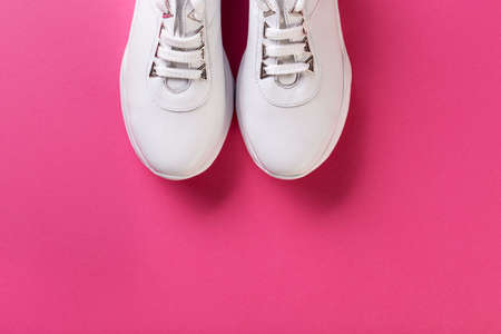 white fashion sneakers on a thick sole, on a pink background.