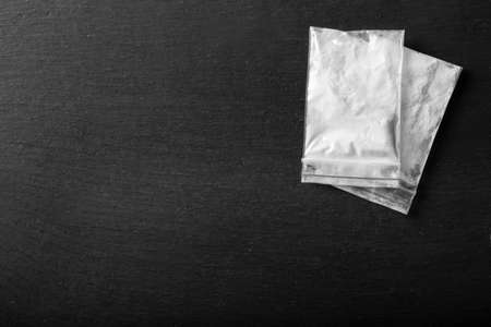 drug powder in a plastic bag on a black background. illegal drug trafficking. place for text