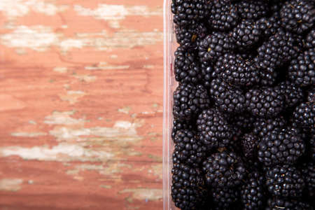 ripe blackberry in a box on a wooden background. place for text