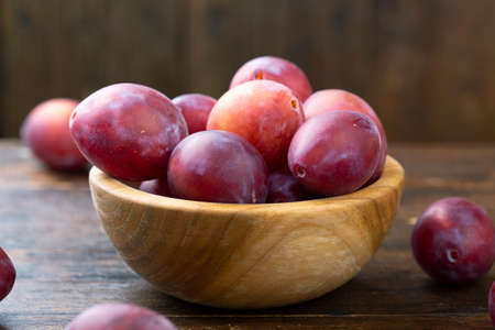Ripe plums in a wooden bowl. Fresh fruits.の写真素材