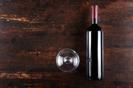 closed bottle of wine and a glass on a brown wooden background. place for text. bottle without label
の写真素材