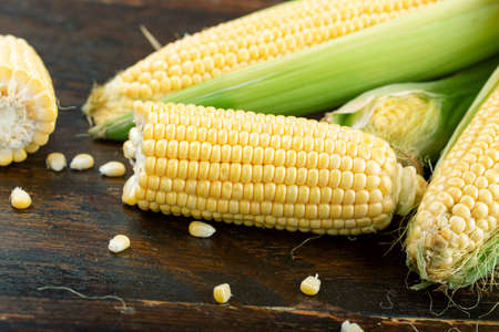 Fresh corn on cobs on wooden table, closeup, top view