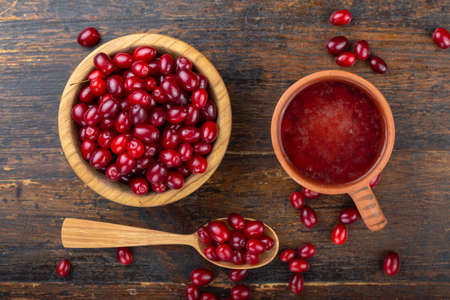 dogwood berries drink and fresh dogwood in a wooden plate on a wooden backgroundの写真素材