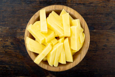 raw julienced potatoes in a plate on a brown wooden background. cooking french fries.の写真素材