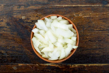 finely chopped raw onions in a plate on a brown wooden background. view from aboveの写真素材
