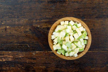 diced zucchini in a wooden plate on a brown wooden backgroundの写真素材