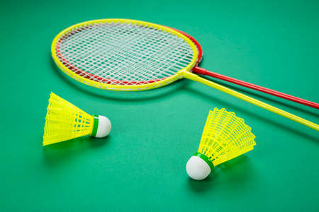 two badminton rackets with a shuttlecock lie on a green backgroundの写真素材