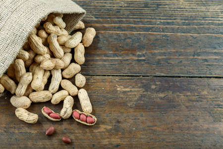 Inshell peanuts in burlap, on brown wooden background. place for text
の写真素材