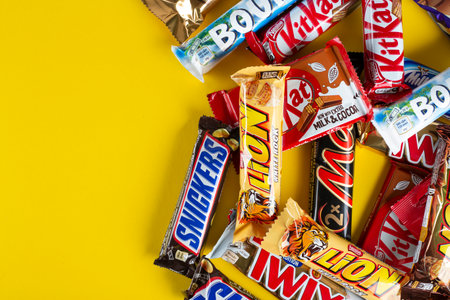 Ukraine, Kyiv - March 23, 2020: A bunch of chocolate bars, including Snickers, Twix, Milka, Kitkat, Lion,  M&M,  Bounty,  on a yellow background.のeditorial素材