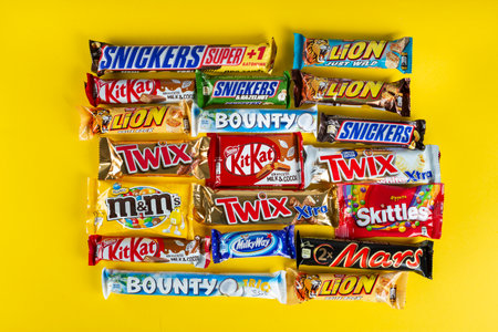 Ukraine, Kyiv - March 23, 2020: A bunch of chocolate bars, including Snickers, Twix, Milka, Kitkat, Lion,  M&M,  Bounty,  on a yellow background.のeditorial素材