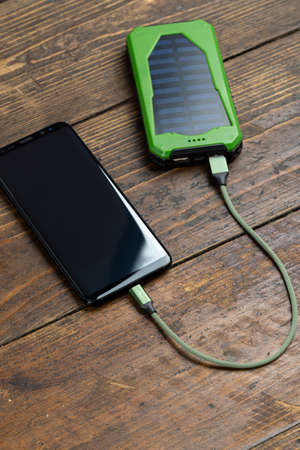 Smartphone charging with power bank on wood boardの写真素材