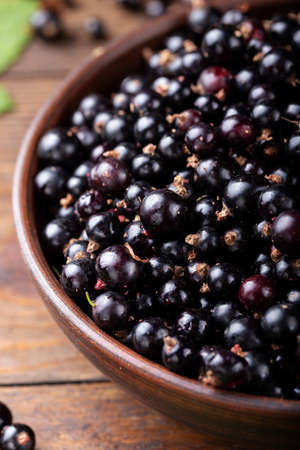 Black currants in the brown bowl on a wooden  table.の写真素材