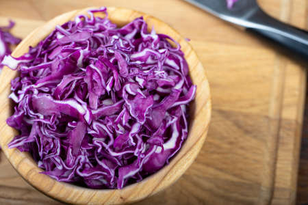 finely chopped purple cabbage in a wooden plate. on a brown wooden background. place for textの写真素材