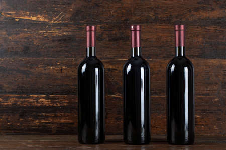 Three red wine bottle on a wooden background.の写真素材