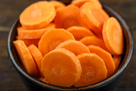 Sliced carrots in a bowl on a wooden background. Vegetable, ingredient and staple food. Healthy food.の写真素材