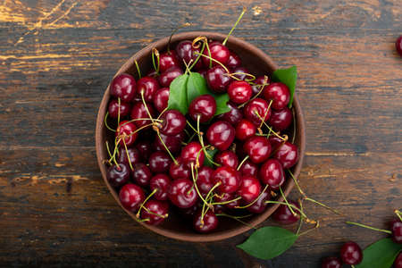 Sweet cherry in a plate on a wooden table.