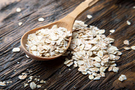 uncooked oatmeal in spoons brown wooden background. place for textの写真素材