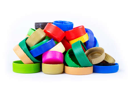 Group of multi colored bottle caps on a white background.
