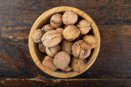 Walnut in wooden bowl on black background with copy space. Top view.の写真素材